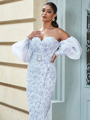 Woman wearing a light blue lace dress with white sleeves standing against a neutral wall.