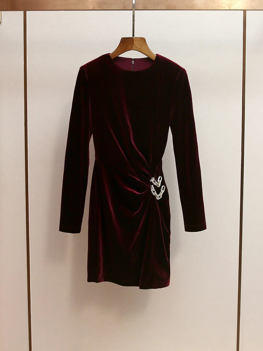 Burgundy velvet dress on a hanger against a neutral background