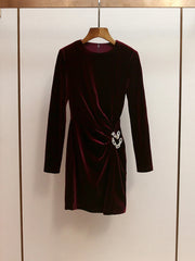 Burgundy velvet dress on a hanger against a neutral background