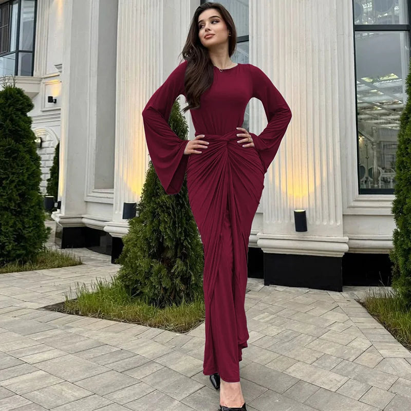 Woman in a burgundy dress standing in front of a classical building.