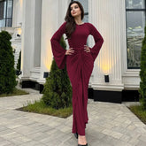 Woman in a burgundy dress standing in front of a classical building.