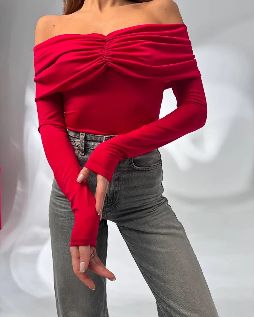 Red off-shoulder top worn by a person on a plain background