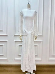 White lace dress on a mannequin against a white paneled wall.