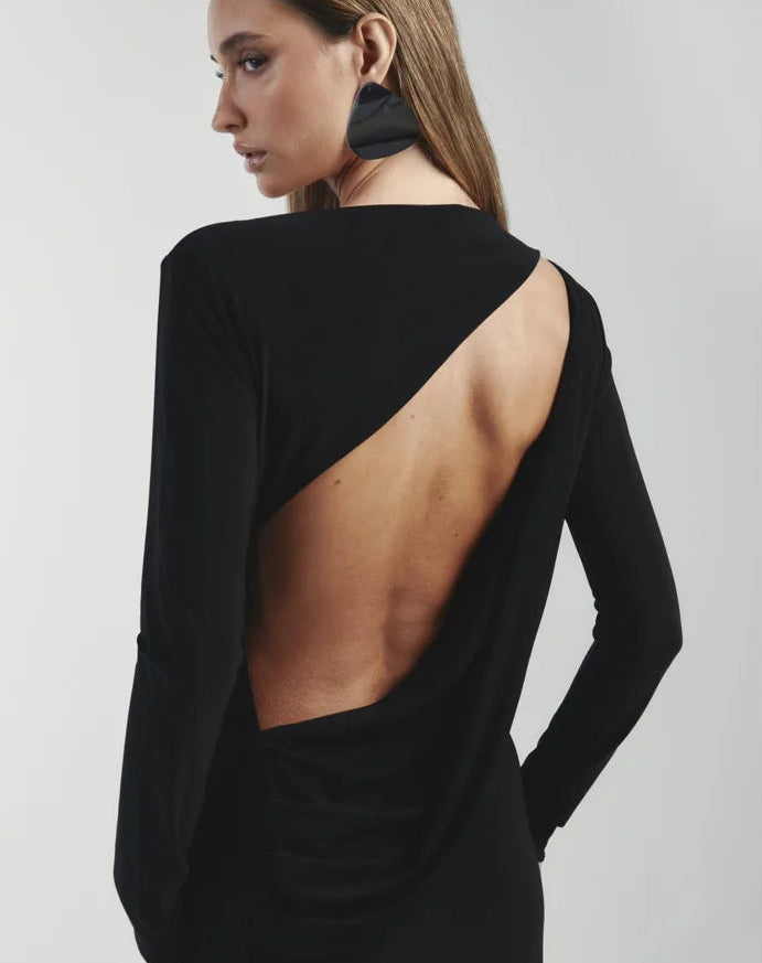 Woman wearing a black dress with an open back on a light gray background