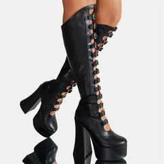 Black platform boots with high heels and detailed laces on a reflective surface.