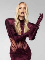 Woman wearing a burgundy dress with sheer panels on a gray background