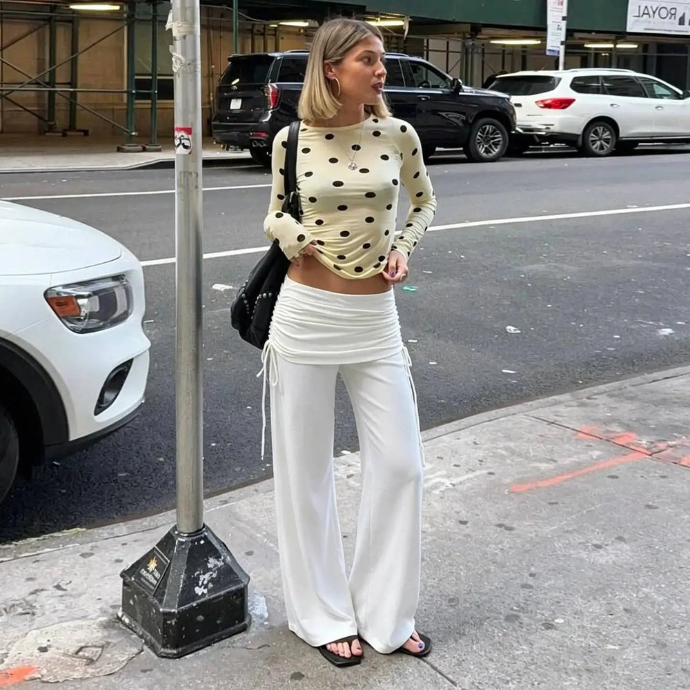 Model wearing solid white wide leg pants with fold over ruched waistband and drawstring detail