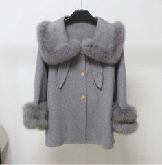 Gray coat with fur trim on a hanger against a white background