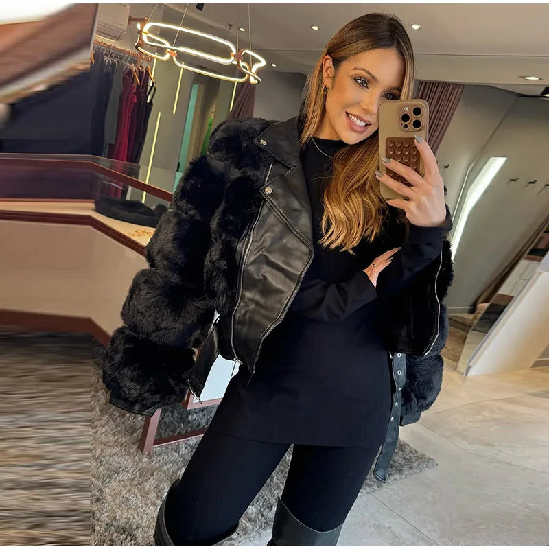 Woman taking a mirror selfie wearing a black fur-lined jacket in a store.