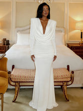 Woman in a white gown standing in a bedroom