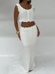 White scalloped edge knit crop top and maxi skirt set worn by a model against a white background.