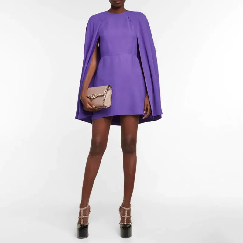 Person wearing a purple dress with a cape on a white background