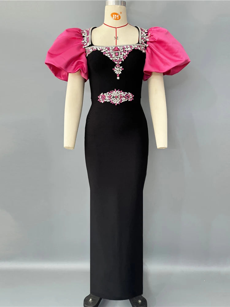 Black evening gown with pink sleeves on a mannequin against a gray background