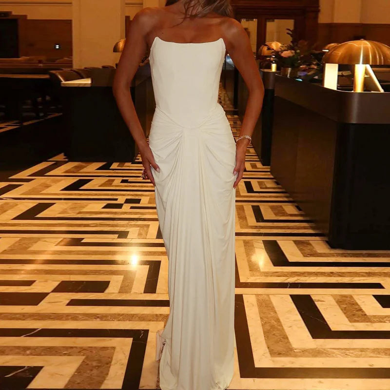 Person wearing a white strapless gown in an elegant indoor setting with a patterned floor.