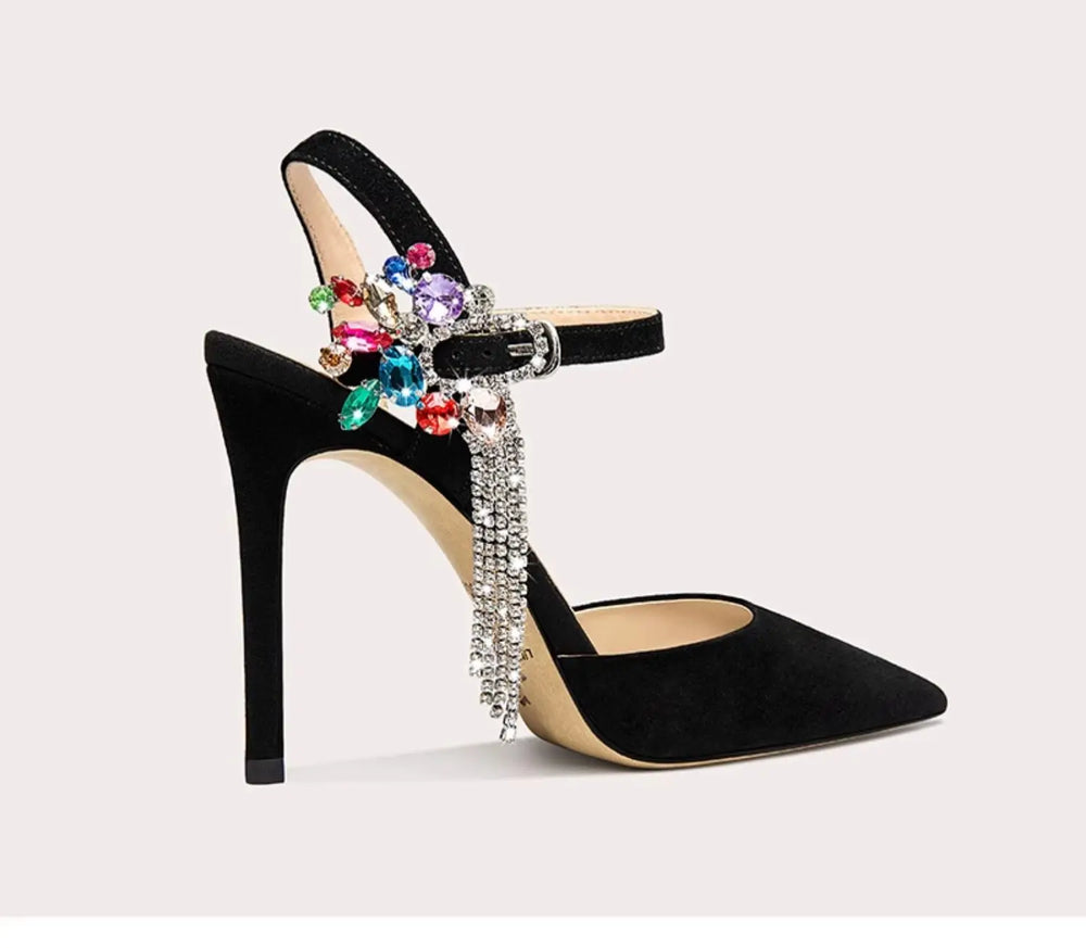 Black high-heeled shoe with colorful gemstones and rhinestones on a light gray background