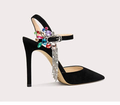 Black high-heeled shoe with colorful gemstones and rhinestones on a light gray background