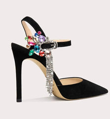Black high-heeled shoe with colorful gemstones and rhinestones on a light gray background