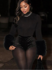 Woman wearing a black outfit with fur cuffs in a dark setting