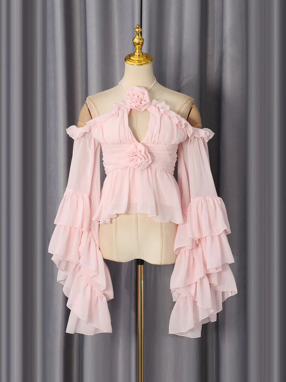Pink two-piece top with ruffled sleeves and floral detail on a mannequin