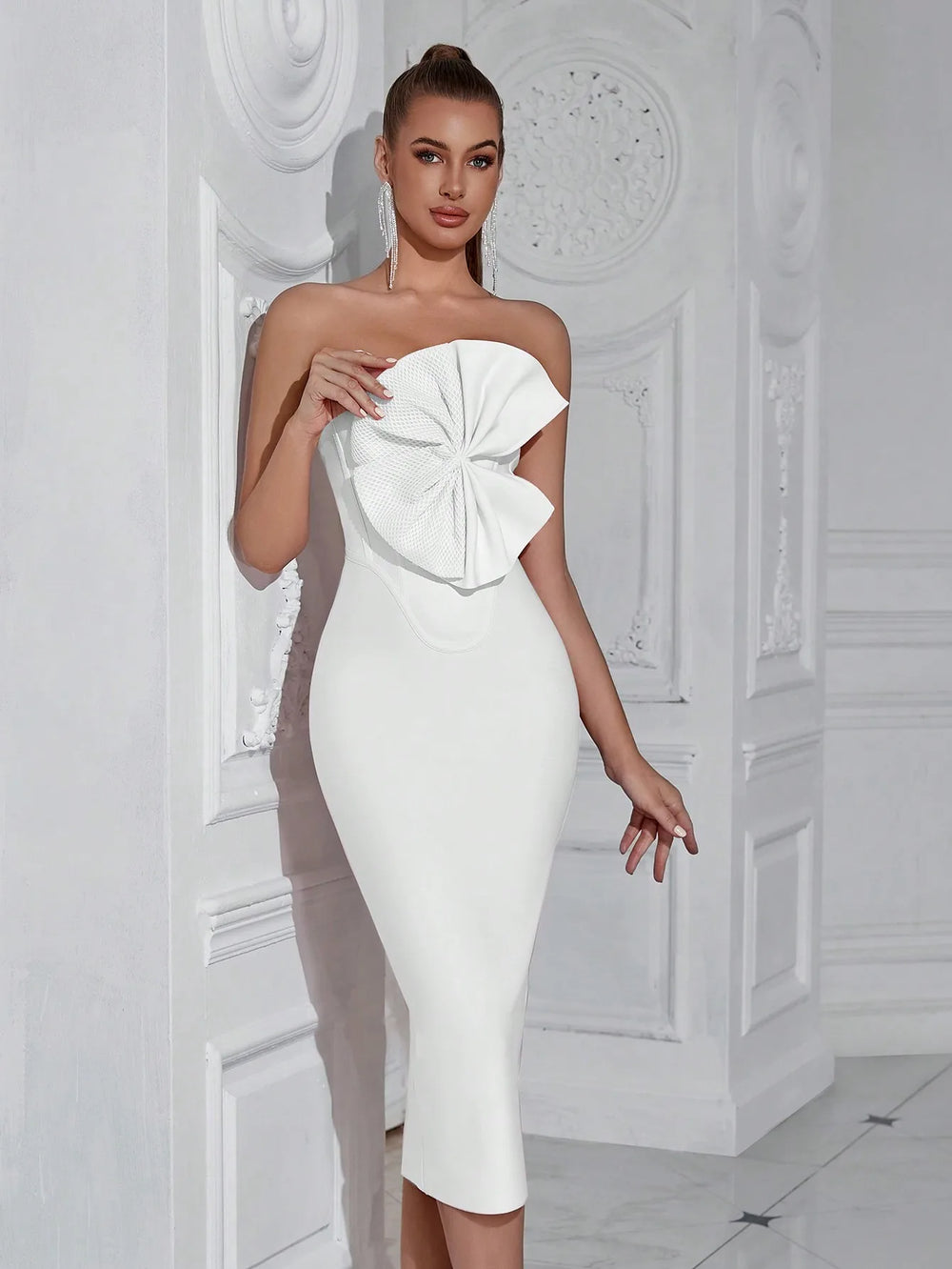 Woman wearing a white strapless dress with a large bow detail in a decorative room.