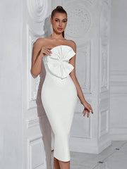 Woman wearing a white strapless dress with a large bow detail in a decorative room.