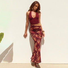 Woman wearing a maroon top and patterned skirt against a white wall.