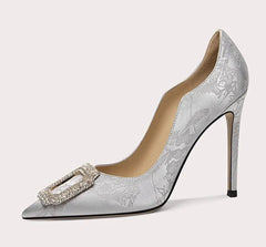 Silver high-heeled shoe with decorative buckle on a white background