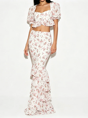 Full body view of a woman in a floral print crop top and ruffle maxi skirt.