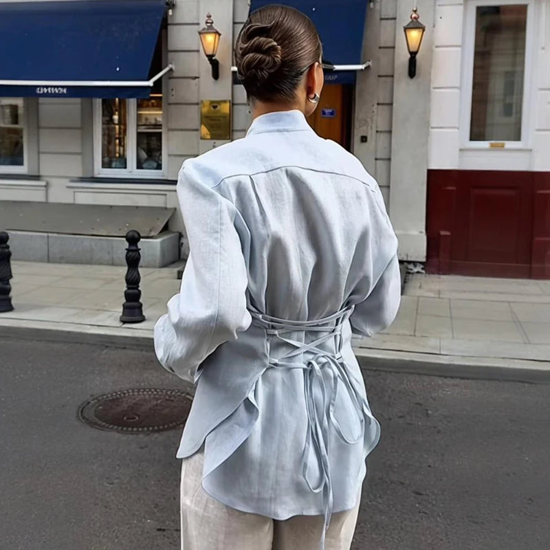 Person wearing a light blue outfit walking on a city street.