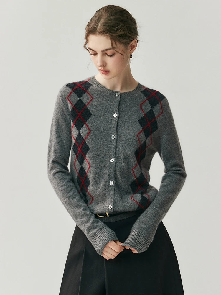 Woman wearing a gray cardigan with red and black argyle pattern on a plain background