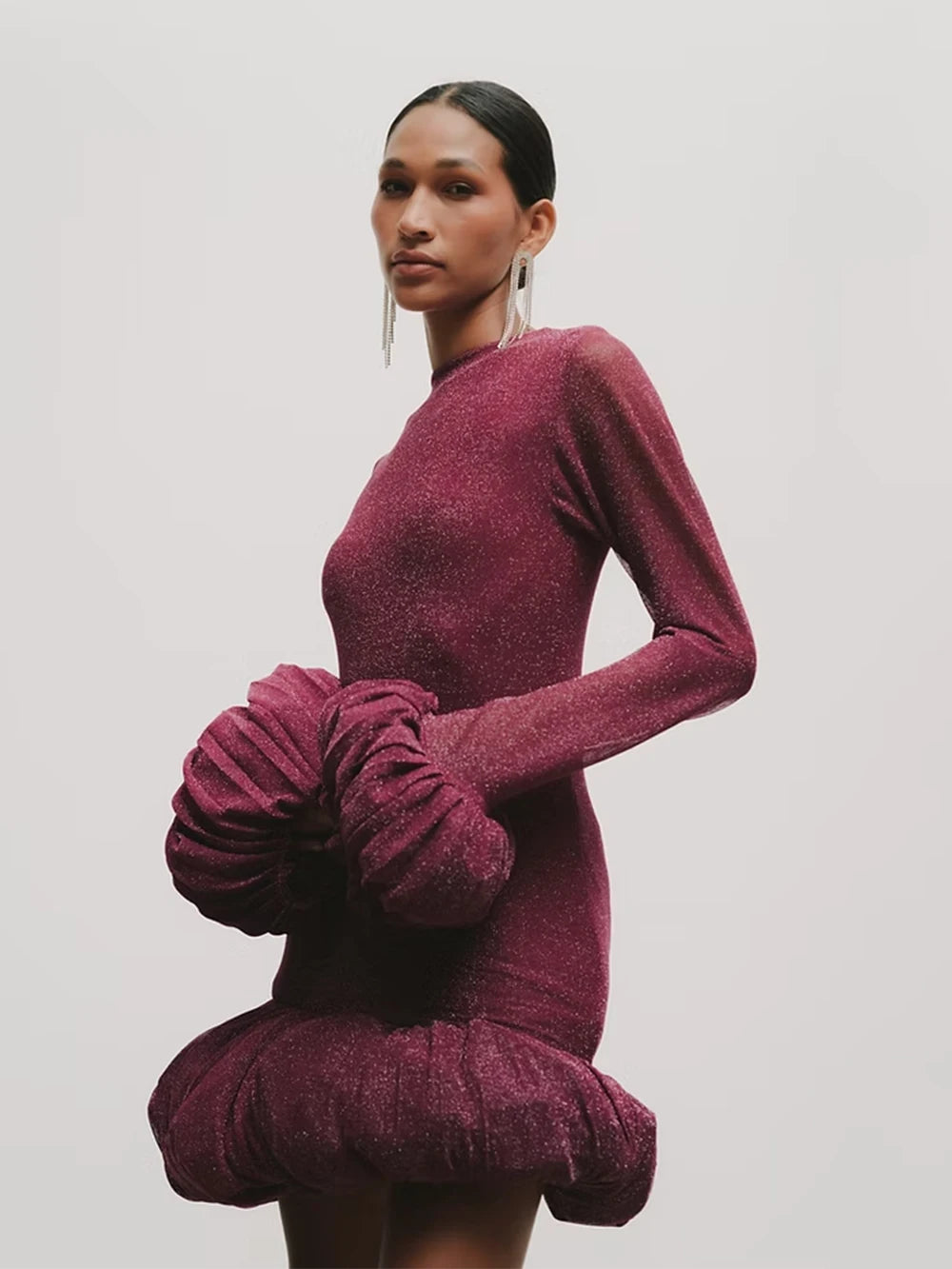 Woman wearing a burgundy dress with ruffled sleeves against a plain background