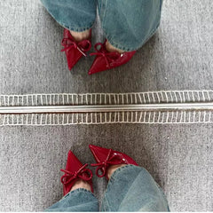 Red shoes with bows worn by a person on a gray carpet.