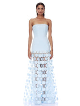 Woman wearing a light blue strapless gown with a unique patterned skirt on a white background