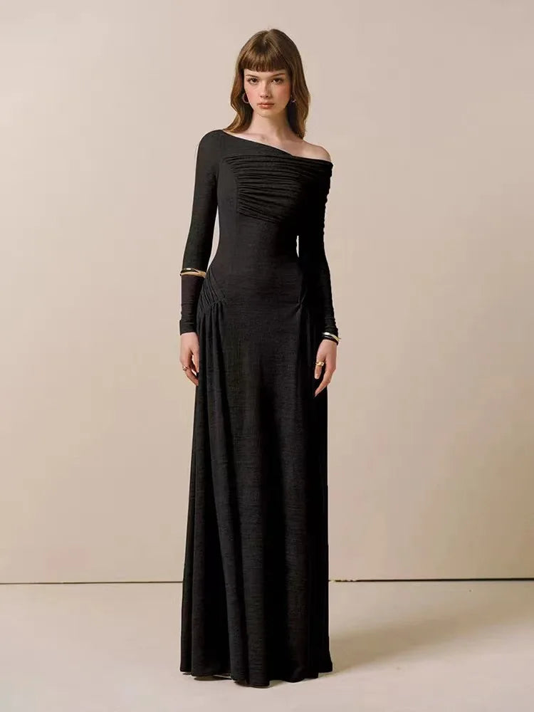 Woman wearing a black off-shoulder long-sleeve gown against a beige background