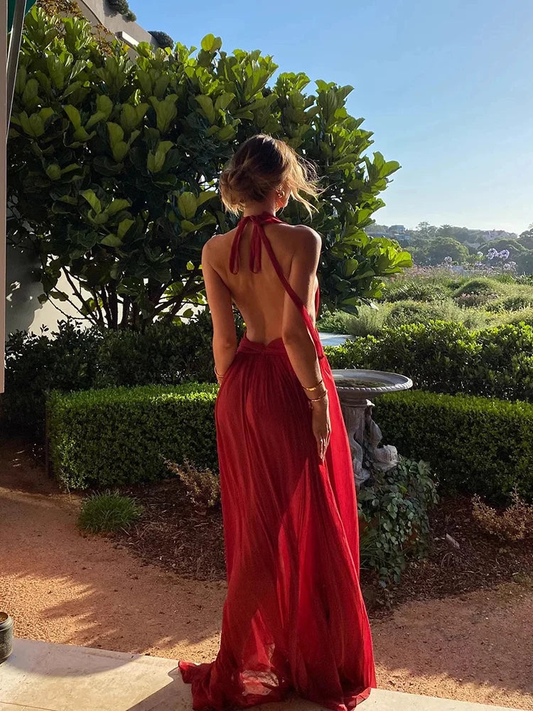 Woman in a red dress standing outdoors with greenery in the background