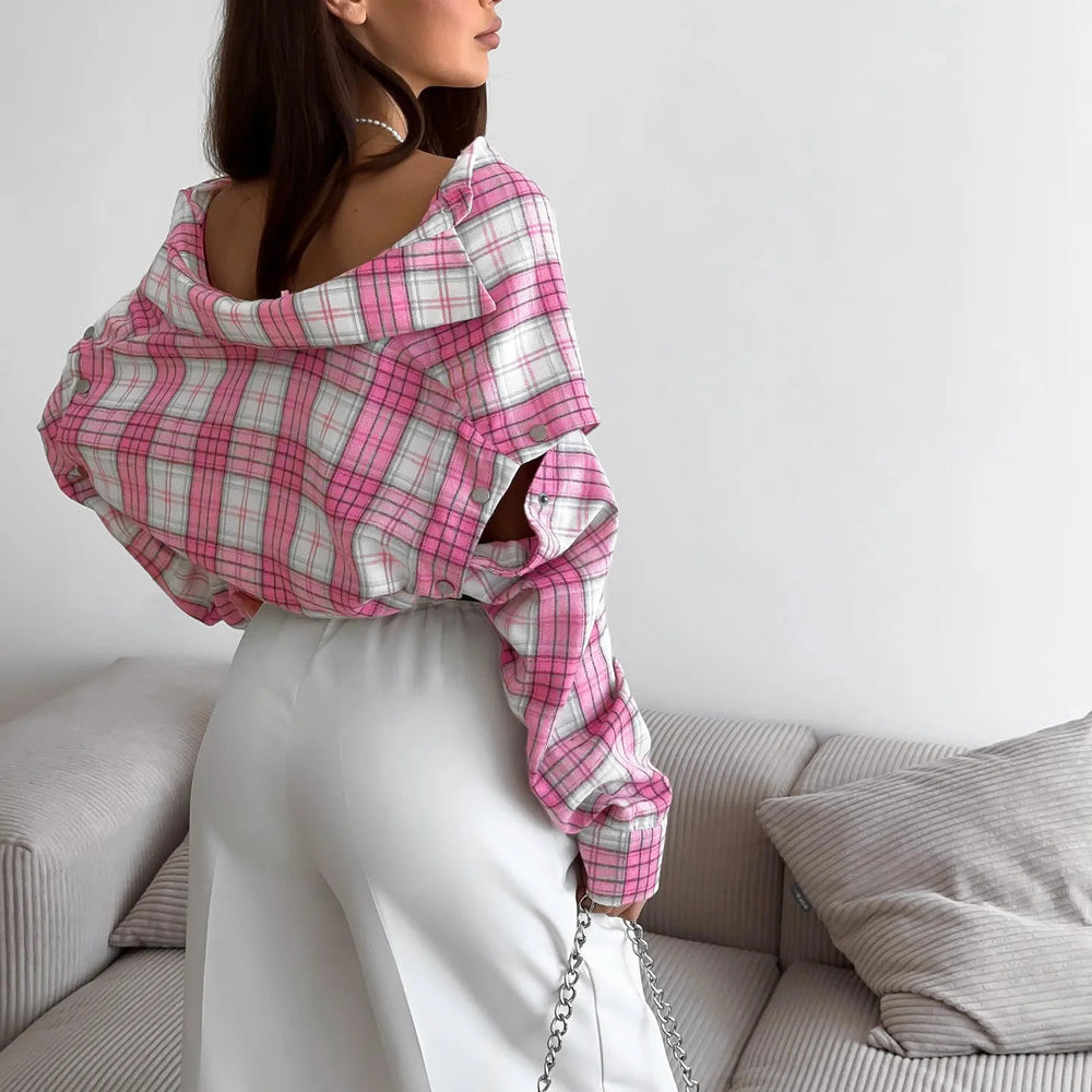 Person wearing a pink and white plaid shirt sitting on a couch.