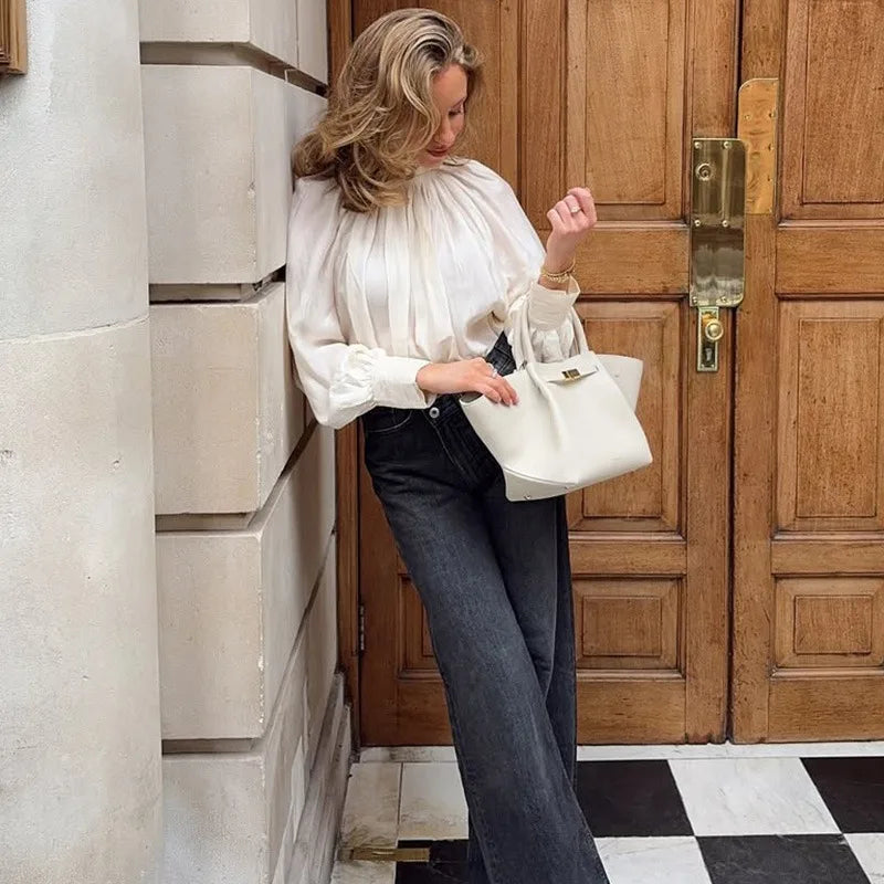 Woman holding a white handbag against a wooden door.
