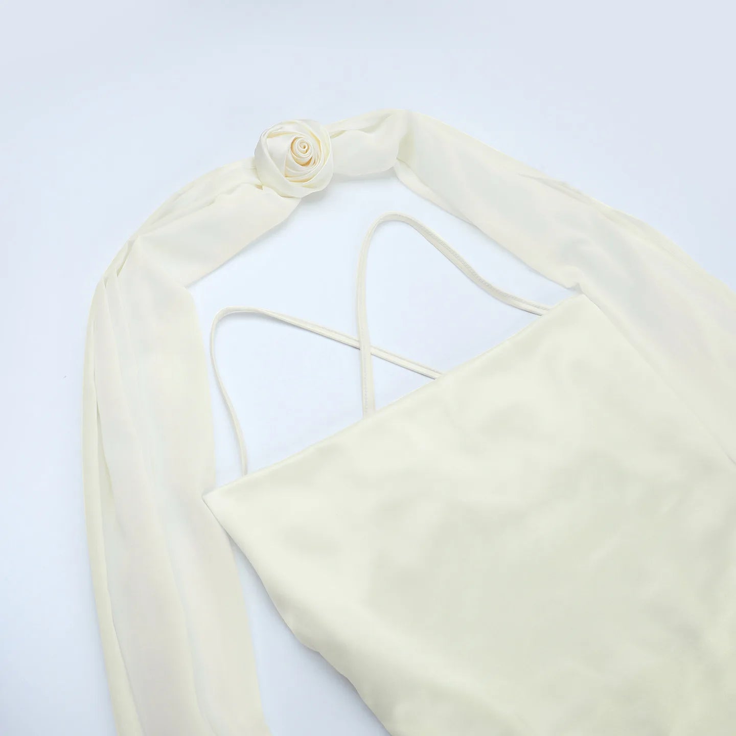 Cream-colored bikini top with thin straps on a light gray background