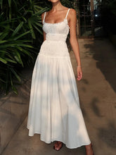 Woman wearing a white dress standing outdoors on a sidewalk.