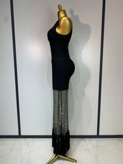 Mannequin wearing a black dress with a sheer skirt against a white wall.