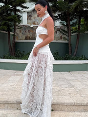 Woman in a white lace dress standing on steps with greenery in the background