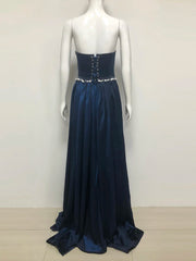 Navy blue evening gown with beaded waist on a mannequin against a white background