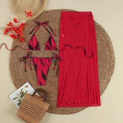 Flat lay of a printed triangle bikini and a red mesh maxi skirt.