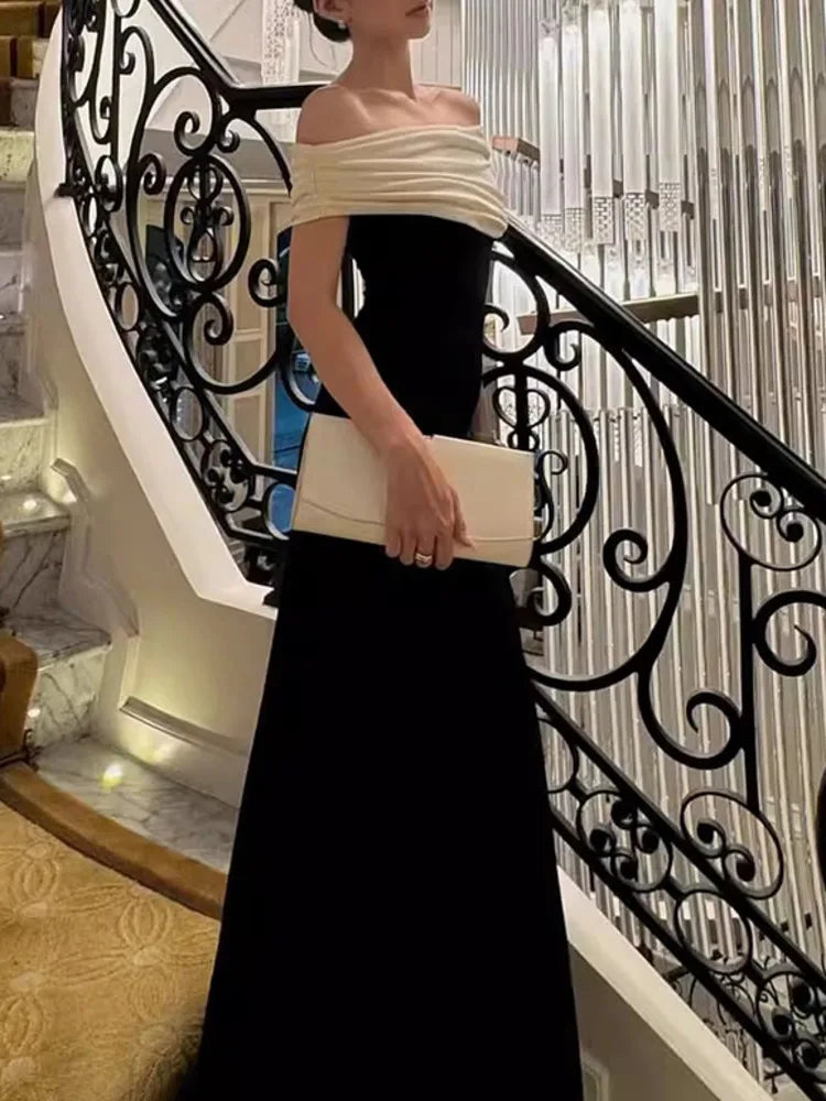 Woman in a black and white dress holding a clutch on a staircase