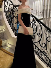 Woman in a black and white dress holding a clutch on a staircase