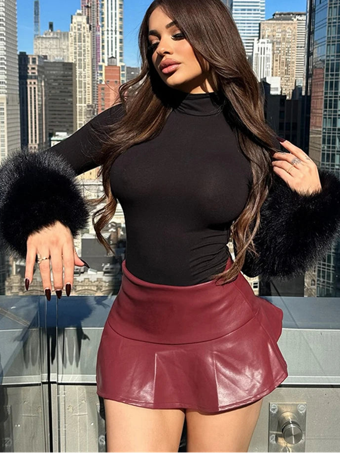 Woman in a black top and red leather skirt with fur cuffs against a city skyline.