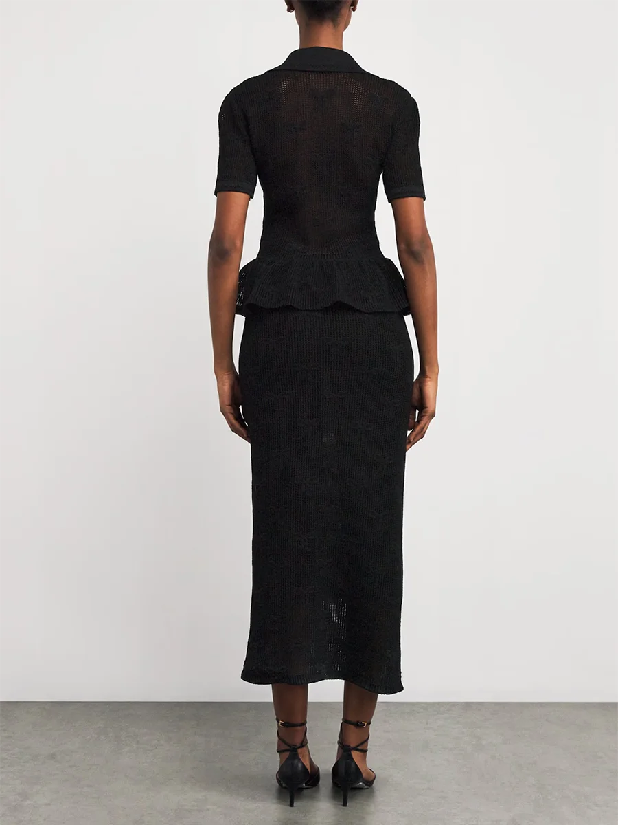 Person wearing a black peplum top and skirt set on a plain background