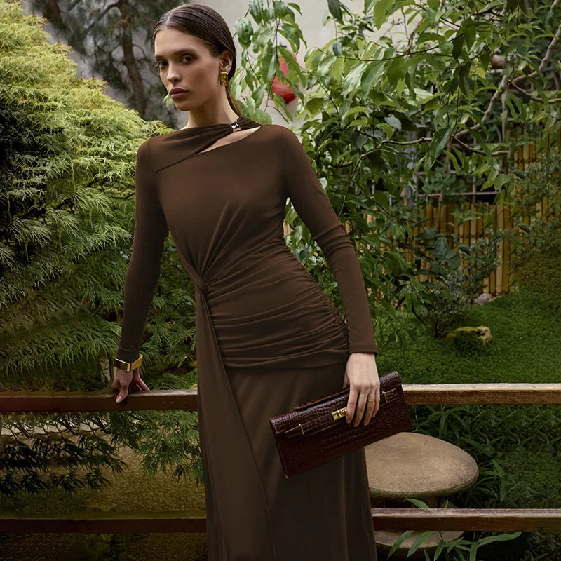 Woman in a brown dress holding a clutch in a garden setting