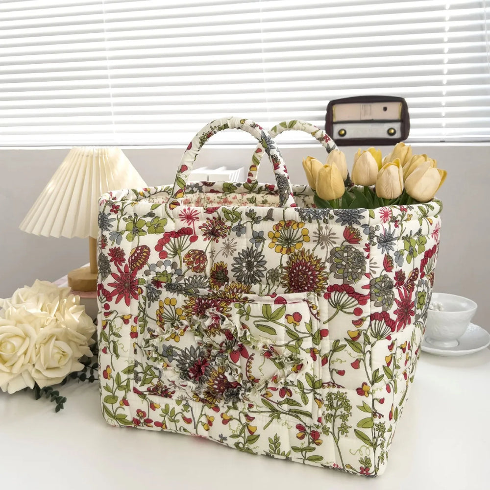 Floral-patterned tote bag with a handle, filled with tulips, on a light surface.