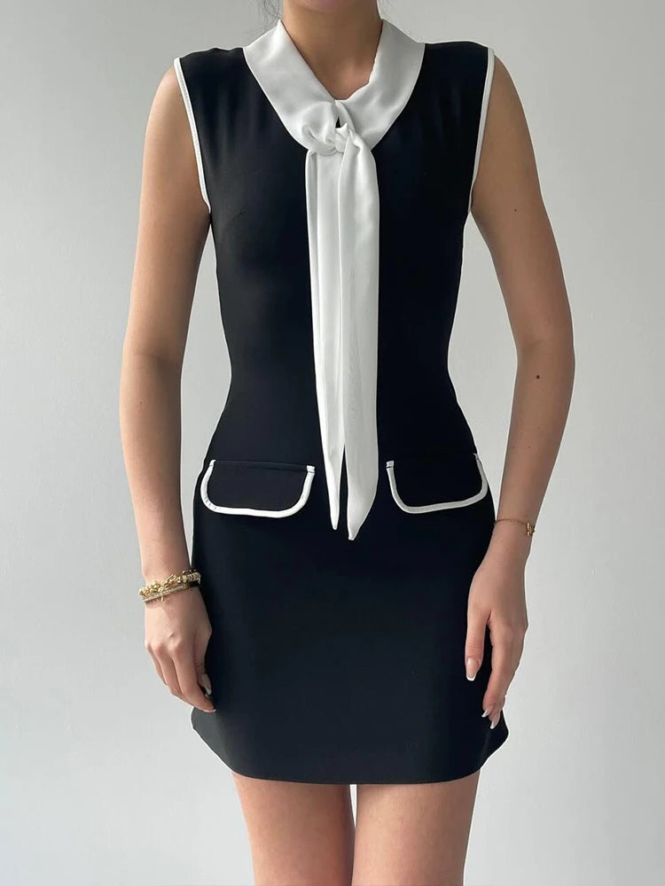 Black dress with white collar and trim on a plain background